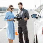 Worker with woman near the broken car on the highway
