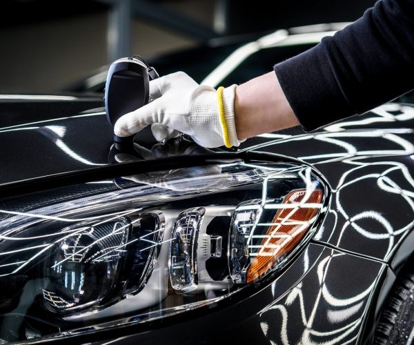Technician Measuring Car Paint Near Headlight Technician Measuring Car Paint Near Headlight